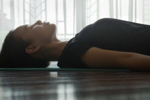 Woman lying on a yoga mat with eyes closed.